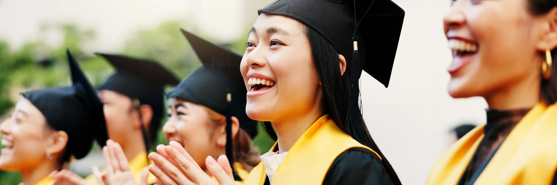 East Asian graduates celebrating and clapping at graduation ceremony